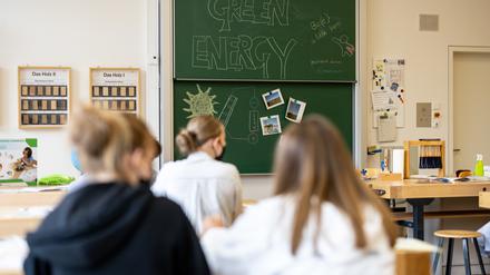 Kinder mit Mund-Nasen-Schutz sitzen im Klassenzimmer.