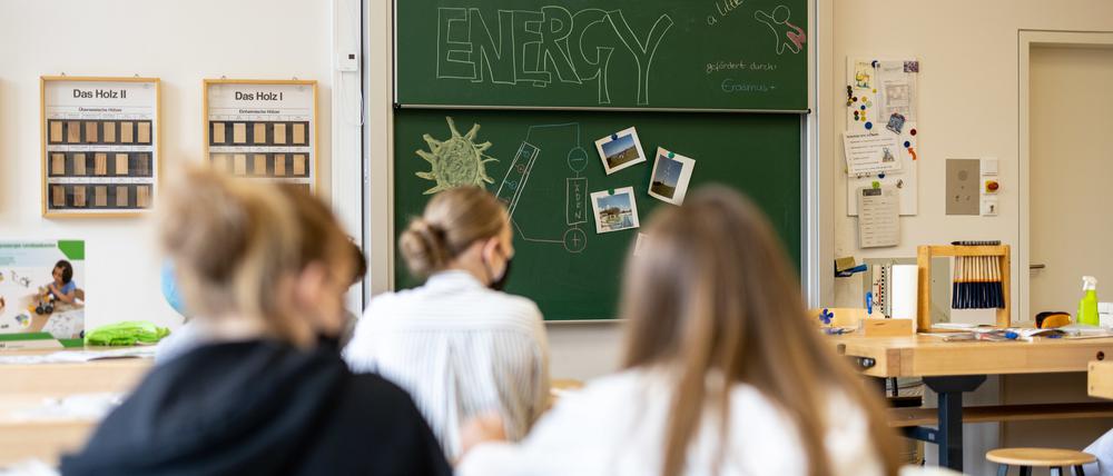 Kinder mit Mund-Nasen-Schutz sitzen im Klassenzimmer.