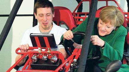 Macht Spaß. Bundeskanzlerin Angela Merkel lässt sich von Alexander Wegner das Elektroauto erklären.