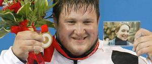 Die Menschen lieben am Sport die großen Gefühle: Der deutsche Gewichtheber Matthias Steiner zeigt nach seinem Olympiasieg 2008 in Peking neben der Goldmedaille und roten Rosen auch ein Foto seiner bei einem Unfall gestorbenen Frau.
