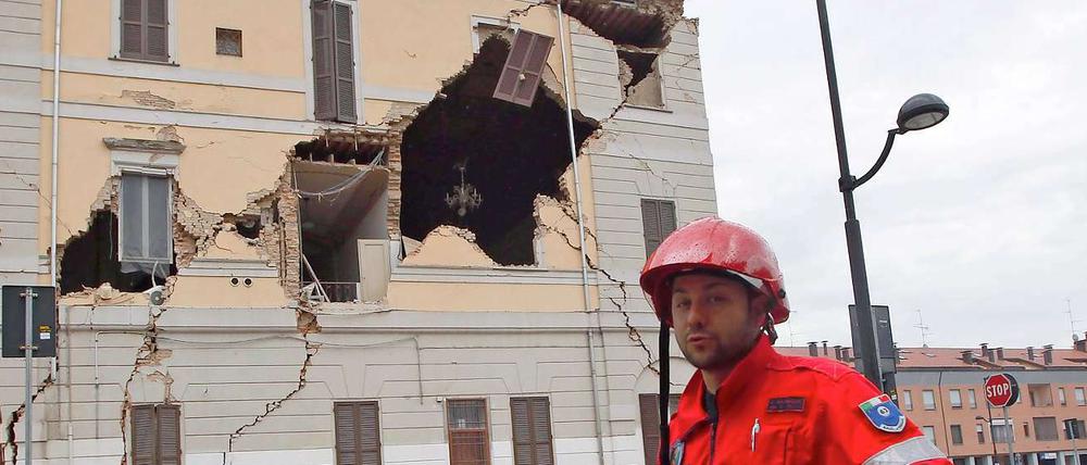Ein Helfer des Katastrophenschutzes geht in St. Agostino an einem beschädigten Haus vorbei.