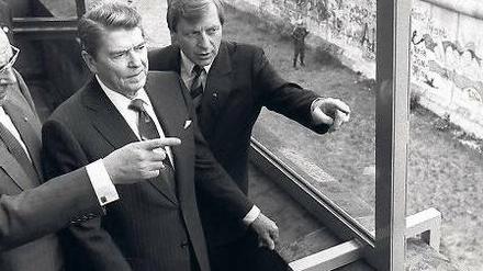 Noch 881 Tage. So lange dauerte es nach Reagans Besuch, bis die Mauer fiel. Hier wirft er vom Reichstag aus einen Blick darauf, flankiert von Kohl (li.) und Diepgen.
