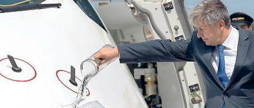 Pitschnasser Vogel. Wowereit kippte am Dienstag Wasser auf den A 380. Das passte zu der etwas bizarren Taufe, denn eigentlich sollte sie ja zwei Tage vor der großen Eröffnungsfeier in BER stattfinden. Es kam bekanntlich anders. Foto: dpa/Wolfgang Kumm