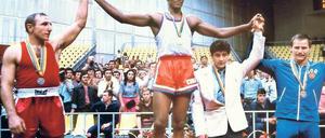 Olympiasieger. Auch 1980 gewinnt die kubanische Box-Legende Teofilo Stevenson in Moskau die Goldmedaille – zum dritten Mal hintereinander. Auf dem Bild neben ihm stehen Pyotr Zaev aus der ehemaligen Sowjetunion und der Ostdeutsche Jürgen Fanghänel, der für die DDR Bronze gewann. Foto: AFP