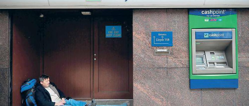 Kreislauf. Eine Obdachloser in London liegt im Eingang der Bank Lloyds TSB, die mit Steuergeldern gerettet werden musste. Die Briten bezahlen die riskanten Bankgeschäfte und Staatsschulden der Vergangenheit mit harter Sparpolitik – fast klaglos. Foto: AFP