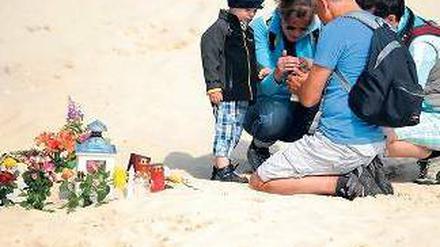 Gedenken. Eine Familie zündet in der Nähe des Unglücks eine Kerze an. Foto: dpa