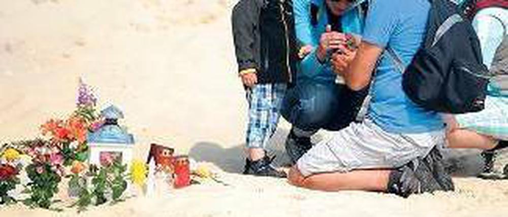 Gedenken. Eine Familie zündet in der Nähe des Unglücks eine Kerze an. Foto: dpa