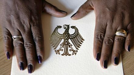 Die Hände einer Neubürgerin liegen im Rathaus Berlin-Neukölln während einer Feierstunde auf einer Einbürgerungsurkunde der Bundesrepublik Deutschland.