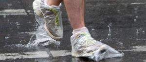 Regen in Berlin, Plastiktüten an den Füßen: Hier schützt sich ein Passant vor der Nässe.