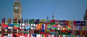 Auf der Wiese vor dem Uhrenturm Big Ben verschiedene Nationalflaggen.