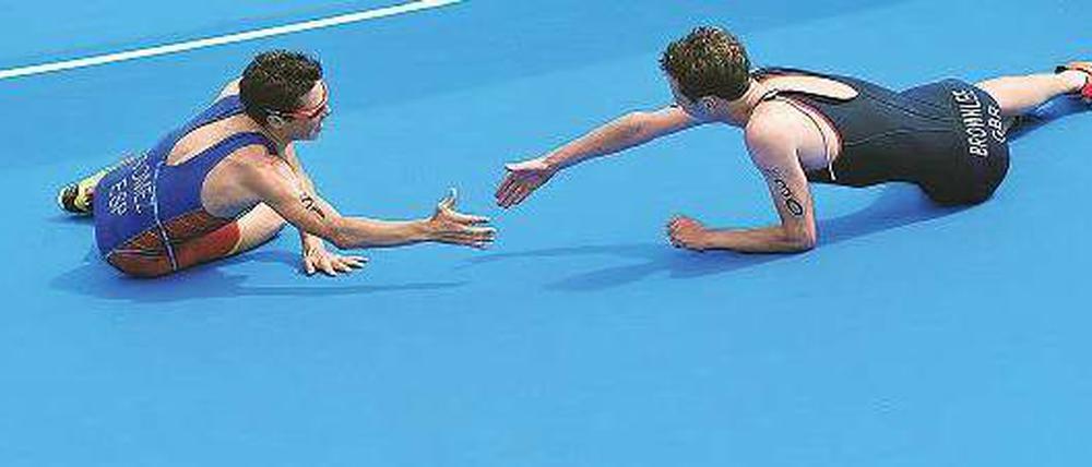 Habe die Ehre! Javier Gomez (links) gratuliert dem im Ziel kollabierten Alistair Brownlee zum Olympiasieg. Foto: dpa