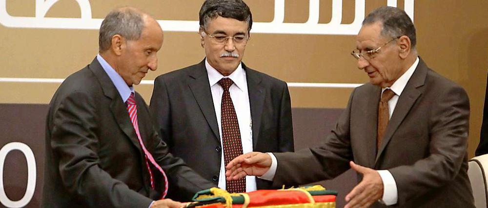 Mustafa Abdel Dschalil (links) übergibt die libysche Flagge an den Parlamentarier Mohammed Ali Salim.