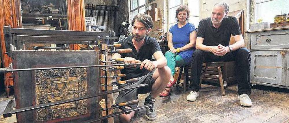 In der Schraubzwinge. Sonst leisten Restaurator Michael Wintjen (links) in seiner Friedenauer Werkstatt nur Möbel wie diese alte Truhe aus Myanmar Gesellschaft. Sonnabend lassen sich auch die Lesenacht-Organisatorin Sabine Würich und Schriftsteller Bernd Schroeder in seiner von Patina überzogenen Werkstatt blicken. Und natürlich die Zuhörer. 