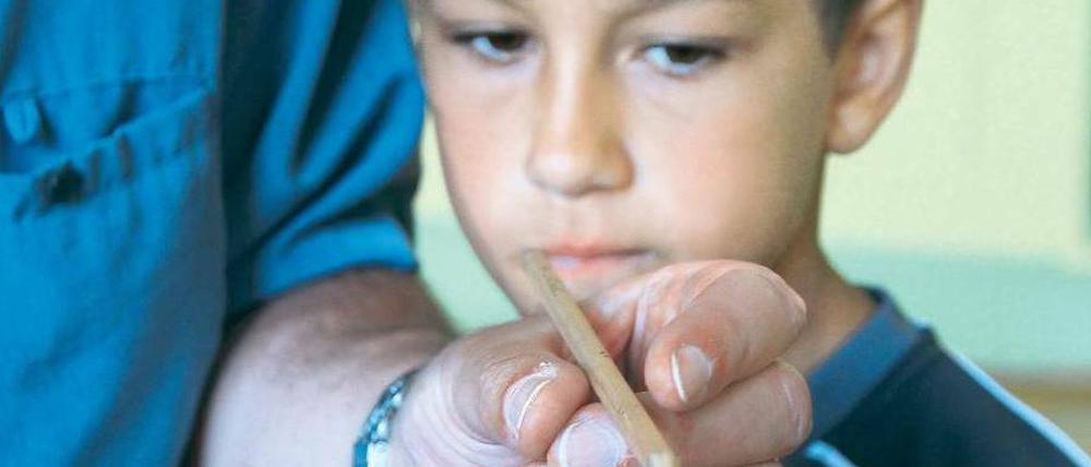 Lesepate Karl-Eugen Denner zeigt einem Schüler die richtige Stifthaltung.