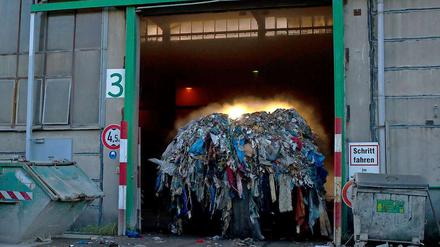 Ein Radlader kommt mit qualmendem Müll aus der Recyclinganlage in Adlershof. 