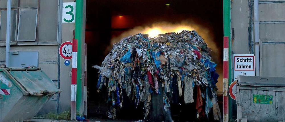 Ein Radlader kommt mit qualmendem Müll aus der Recyclinganlage in Adlershof. 