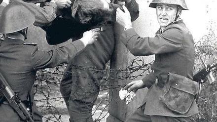 Ein Foto für den Geschichtsunterricht: Eines der bekanntesten Maueropfer, Peter Fechter, wird nach seinem missglückten Fluchtversuch und einer Ewigkeit, die er in seinem Blut lag, von einem Grenztrupp aus dem Todesstreifen geholt. Zu diesem Zeitpunkt lebte er noch. Links: Hauptmann Schäfer und Oberfeldwebel Wurzel (unten); rechts: Volkspolizeiobermeister Mularczyk, darunter Gefreiter Lindenlaub.