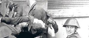 Ein Foto für den Geschichtsunterricht: Eines der bekanntesten Maueropfer, Peter Fechter, wird nach seinem missglückten Fluchtversuch und einer Ewigkeit, die er in seinem Blut lag, von einem Grenztrupp aus dem Todesstreifen geholt. Zu diesem Zeitpunkt lebte er noch. Links: Hauptmann Schäfer und Oberfeldwebel Wurzel (unten); rechts: Volkspolizeiobermeister Mularczyk, darunter Gefreiter Lindenlaub.