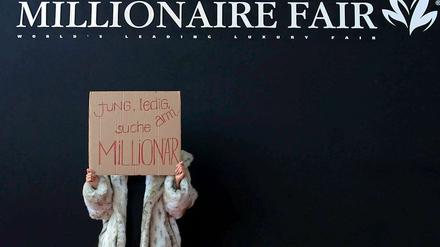 Klare Ansage. An das Geld der Millionäre will nicht nur diese junge Frau vor einer Luxusmesse in München. Die könnten aber bald ein bisschen weniger Geld haben. 