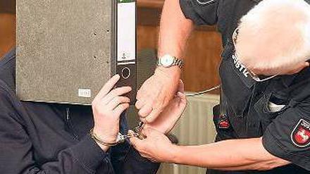 Versteckt sich hinter einem Ordner. Der Angeklagte David H. am Montag im Gerichtssaal von Aurich. Foto: dpa