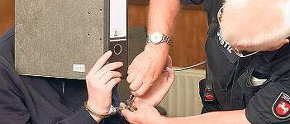 Versteckt sich hinter einem Ordner. Der Angeklagte David H. am Montag im Gerichtssaal von Aurich. Foto: dpa