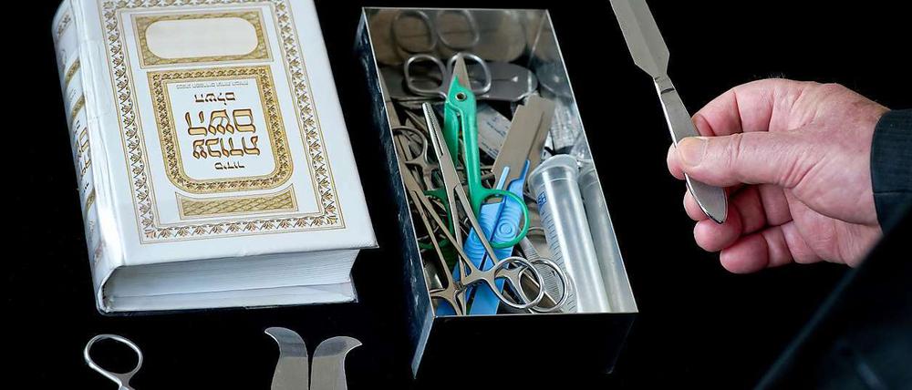 Ein Rabbiner hält in den Räumen der Israelitischen Kultusgemeinde in Hof ein Beschneidungsmesser, daneben liegt ein hebräisches Altes Testament. Das medizinische Besteck benötigt der Mohel (Beschneider) für die Brit Mila, die rituelle jüdische Beschneidung.