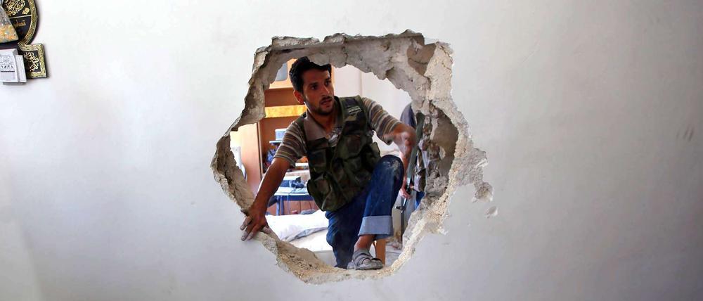Ein Durchbruch? Der syrische Vizepremier hat den Rücktritt Assads als verhandelbar bezeichnet. Dieser Rebellenkämpfer bricht zunächst nur in den nächsten Raum durch - auf der Suche nach Überlebenden in einem in Teilen zerstörten Haus.