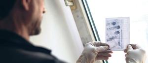 Ein Ermittler untersucht Fingerabdrücke.