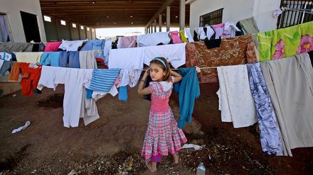 Mehrere Millionen Syrer sind auf der Flucht. Dieses syrische Mädchen hängt in einem Camp an der Grenze zur Türkei Wäsche auf.