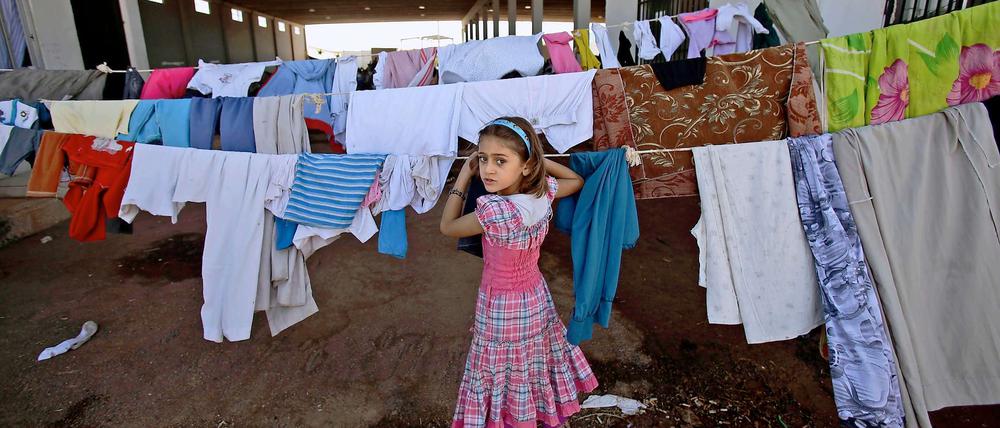 Mehrere Millionen Syrer sind auf der Flucht. Dieses syrische Mädchen hängt in einem Camp an der Grenze zur Türkei Wäsche auf.