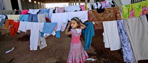Mehrere Millionen Syrer sind auf der Flucht. Dieses syrische Mädchen hängt in einem Camp an der Grenze zur Türkei Wäsche auf.