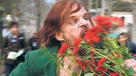 Maskenspieler. Monsieur Merde (Denis Lavant) futtert Friedhofsblumen.