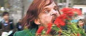 Maskenspieler. Monsieur Merde (Denis Lavant) futtert Friedhofsblumen. 