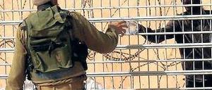 Hilfsbereit. Ein israelischer Soldat versorgt eritreische Flüchtlinge im Niemandsland zu Ägypten mit Wasser. Keines der beiden Länder will sie einreisen lassen. Foto Yehuda Lahiani/dpa