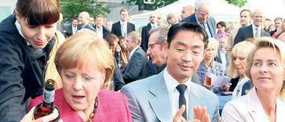 Darf’s ein Tropfen mehr sein? Kanzlerin Angela Merkel (v.li.) mit ihren Ministern Philipp Rösler und Ursula von Leyen beim Sommerfest der Landesvertretung Niedersachsen in Berlin.