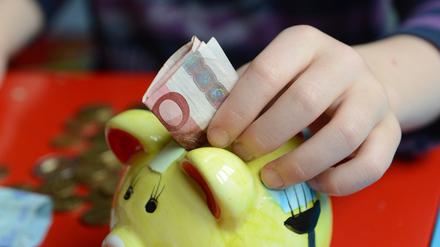ARCHIV - ILLUSTRATION - Ein fünfjähriger Junge steckt einen Zehn-Euro-Schein in sein Sparschwein, aufgenommen am 10.04.2012 in Berlin. (zu dpa «Umfrage: Mehrheit schaut zufrieden aufs Bankkonto» vom 24.10.2017) Foto: Gregor Fischer +++(c) dpa - Bildfunk+++