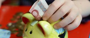 ARCHIV - ILLUSTRATION - Ein fünfjähriger Junge steckt einen Zehn-Euro-Schein in sein Sparschwein, aufgenommen am 10.04.2012 in Berlin. (zu dpa «Umfrage: Mehrheit schaut zufrieden aufs Bankkonto» vom 24.10.2017) Foto: Gregor Fischer +++(c) dpa - Bildfunk+++