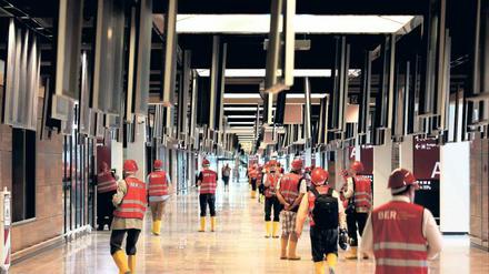 Während der Ila wurden Reporter über die Baustelle geführt. Im BER-Terminal sind die Deckenklappen geöffnet; darunter wird an den Kabeltrassen gearbeitet. Die Geräte und Sitzbänke sind mit Schutzfolie geschützt. 