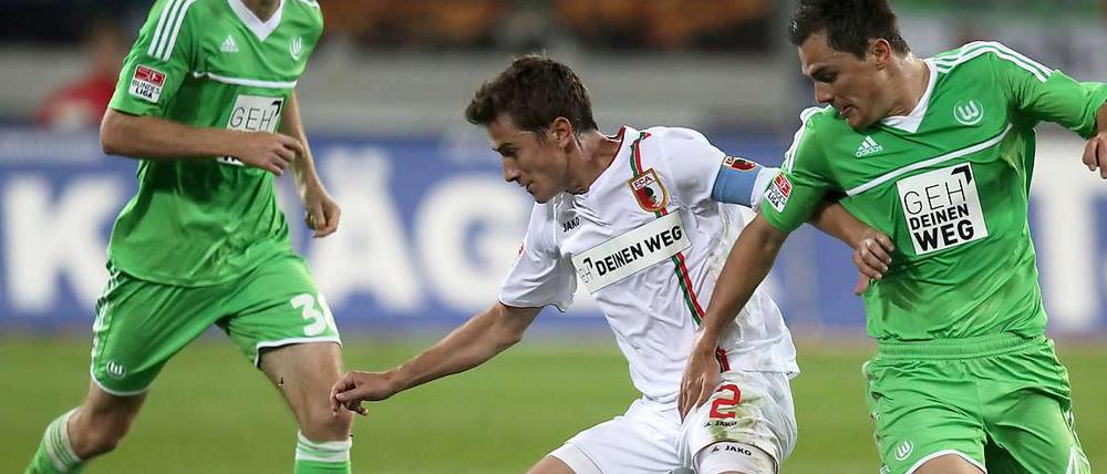 Vergebliches Duell um ein Tor. Augsburgs Paul Verhaegh (l) und Wolfsburgs Marcel Schäfer kämpfen um Ball und Sieg.