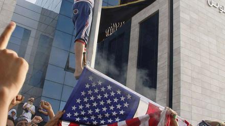 Tunesische Demonstranten verbrennen eine US-Flagge und hissen stattdessen eine islamistische.