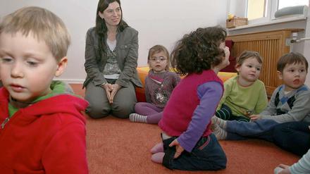 Senatorin Sandra Scheeres schaut zu, wie ein Erzieherin mit Kindern eines INA-Kindergartens singt.