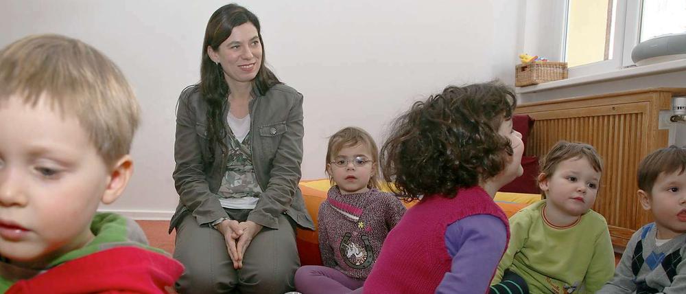 Senatorin Sandra Scheeres schaut zu, wie ein Erzieherin mit Kindern eines INA-Kindergartens singt.