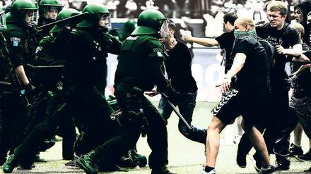 Die Ausrüstung macht den Unterschied. Im Gruppenverhalten sind sich Ultras und Polizisten ähnlich. Die Szene zeigt eine Ausschreitung beim Spiel Eintracht Frankfurt gegen 1860 München im April 2012. Foto: dpa