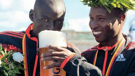 Ein Schluck für den Zweiten. Dennis Kimetto (l.) bekommt vom Marathon-Sieger Geoffrey Mutai etwas Siegerbier.