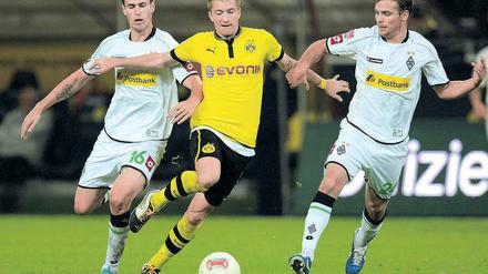 Euch kenn’ ich doch. Marco Reus wird von seinen früheren Kollegen Havard Nordtveit (l.) und Tony Jantschke eskortiert. Foto: AFP