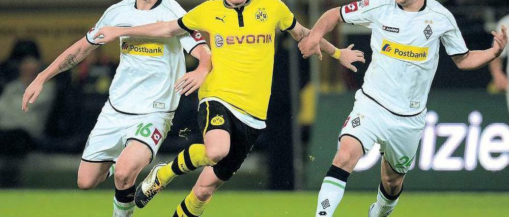 Euch kenn’ ich doch. Marco Reus wird von seinen früheren Kollegen Havard Nordtveit (l.) und Tony Jantschke eskortiert. Foto: AFP