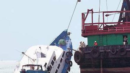 Ein Kran hebt das gesunkene Ausflugschiff aus dem Wasser. 