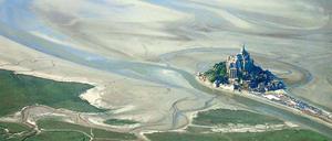 Land in Sicht. Die Vogelperspektive lässt erahnen, welch’ Schicksal Mont Saint-Michel vor der Küste der Normandie droht, weil die Natur außer Kraft gesetzt wurde.