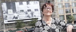 Elke Rosin auf dem Gendarmenmarkt vor einem Grossplakat mit dem Bild ihrer Flucht.