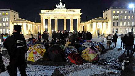 Bei eisigen Temperaturen halten die Flüchtlinge im Hungerstreik auch nachts auf dem Pariser Platz aus. Die mit Protestslogans bemalten Schirme gelten als Kunstgegenstände und dürfen deshalb bleiben. 